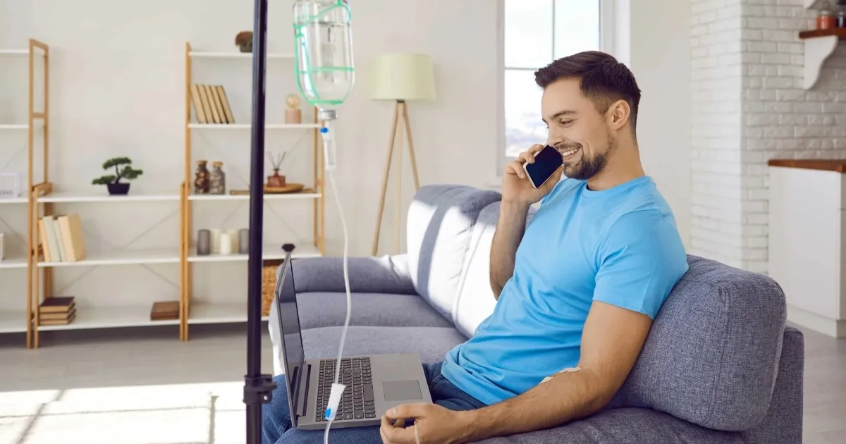 Man receiving IV therapy while working from home at Divine Age Med Spa in Wesley Chapel, FL.